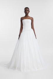 A model wearing the Torres Gown, a strapless ivory gown with an asymmetric structured corset and full tulle skirt.