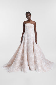 A model wearing the Dalias Gown, a strapless ivory lace ballgown with a structured bodice, full skirt and sweeping train.