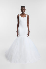 A model wearing the Bossa Gown, a white scoop-neck gown with a fitted bodice and full layered tulle trumpet skirt.