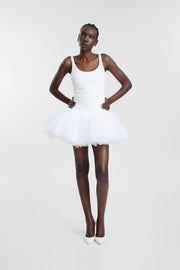 A model wearing the Fiorito Dress, a white mini dress with a scoop neckline, fitted bodice and layered tulle tutu skirt, photographed from the front against a light grey studio background.