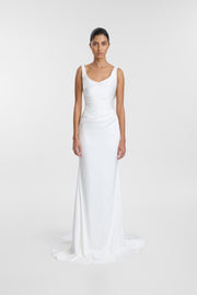 A model wearing the Llume Gown, a floor-length bright ivory satin wedding dress with a scoop neckline, wide straps and soft draping through the waist and hip.