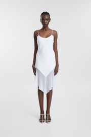 A model wearing the Pacha Dress, a white midi dress with fine spaghetti straps, a scoop neckline and chiffon scarf detailing at the hem.