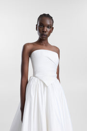A model wearing the Vara Corset, a structured ivory duchess satin strapless bridal top with a modern straight neckline and soft organic draping.