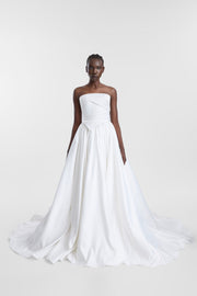 A model wearing the Paloma Skirt, a full floor-length ivory duchess satin and tulle bridal skirt with tightly gathered details and a sweeping train.