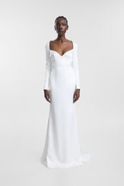 A model wearing the Palma Gown, an ivory silk gown with long sleeves, a fitted empire-line silhouette and fluid floor-length skirt.