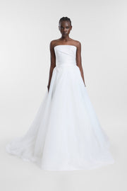 A model wearing the Cala Skirt, a voluminous floor-length bright ivory tulle bridal skirt with a duchess satin waistband, directional draping, and a sweeping train.